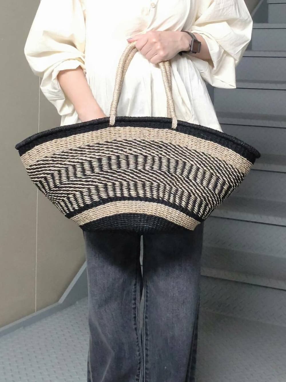 ブラック系のデニムパンツ、ベージュ系のかごバッグ、ホワイト系のシャツ/ブラウスを着用したレディースの春コーディネートの4枚目の写真