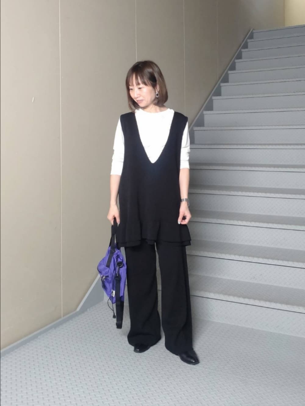 ブルー系のトートバッグ、ホワイト系のTシャツ/カットソー、ブラック系のニット/セーターを着用したレディースの冬コーディネートの2枚目の写真