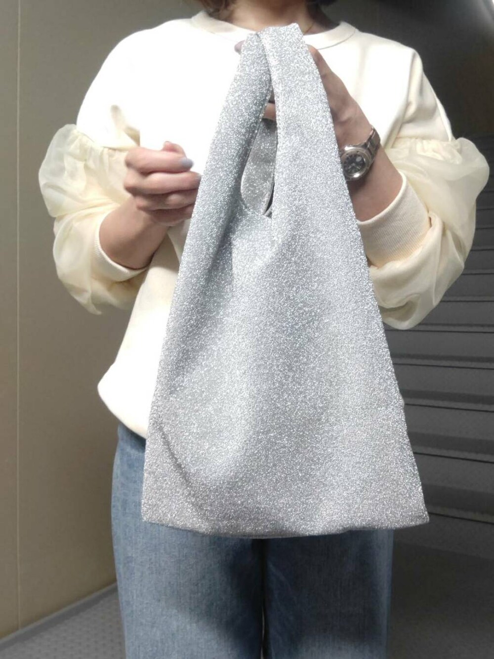 シルバー系のトートバッグ、ブラック系のローファー、ブルー系のデニムパンツを着用したレディースの冬コーディネートの3枚目の写真