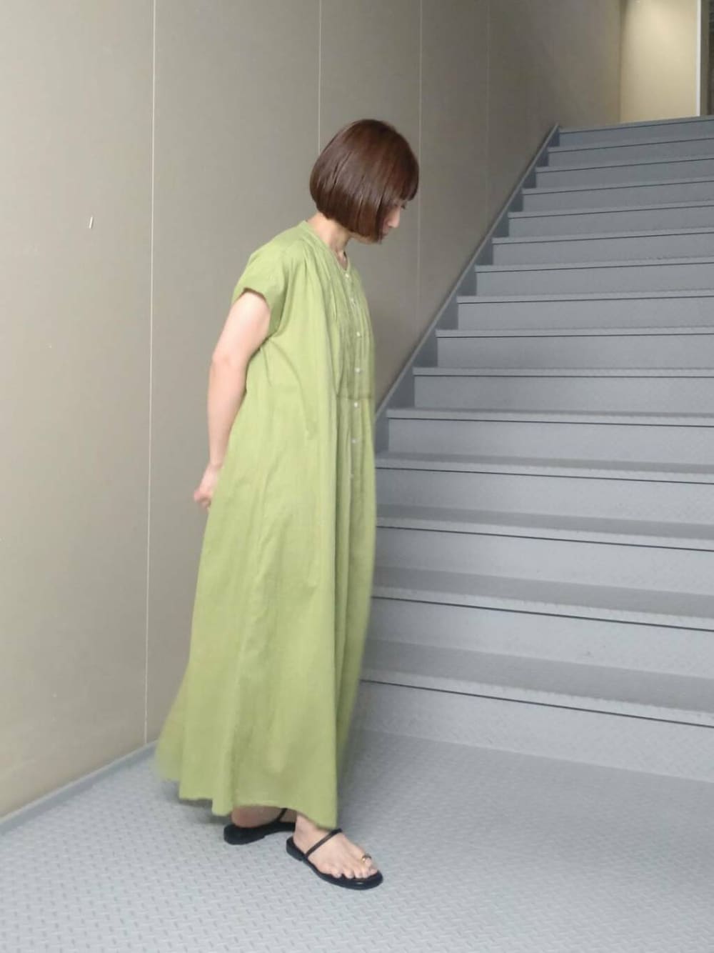 ブラック系のバックパック/リュック、グリーン系のワンピース、ブラック系のサンダルを着用したレディースの夏コーディネートの2枚目の写真