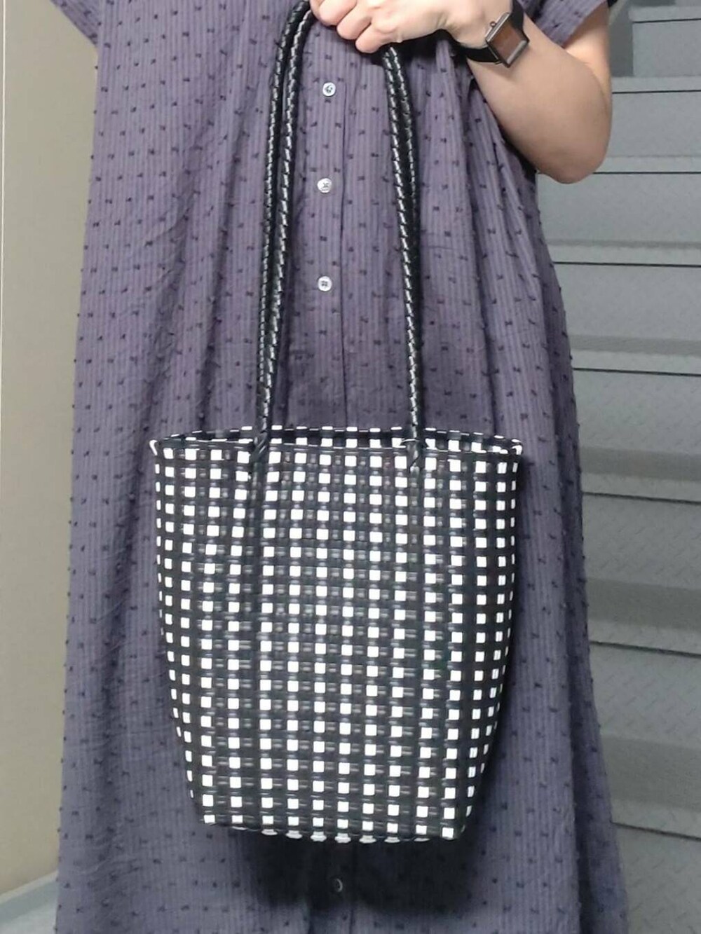 ブラック系のトートバッグ、グレー系のワンピース、ゴールド系のサンダルを着用したレディースの夏コーディネートの3枚目の写真