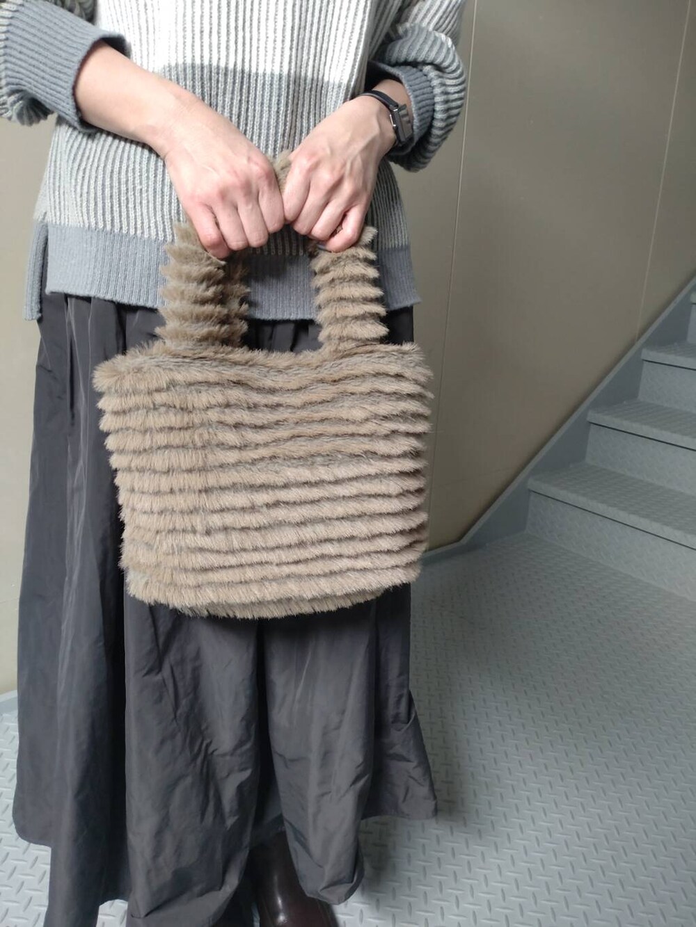 ブラウン系のブーツ、イエロー系のトートバッグ、グレー系のスカートを着用したレディースの冬コーディネートの4枚目の写真