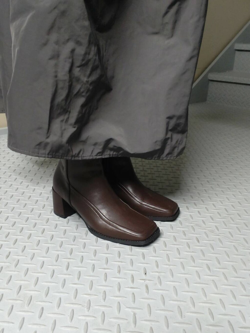 ブラウン系のブーツ、イエロー系のトートバッグ、グレー系のスカートを着用したレディースの冬コーディネートの3枚目の写真