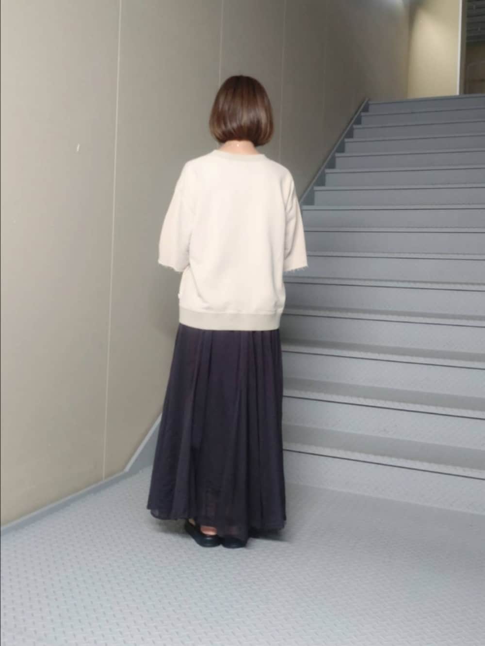 ベージュ系のTシャツ/カットソー、ブラック系のスカート、ブルー系のポーチを着用したレディースの夏コーディネートの3枚目の写真