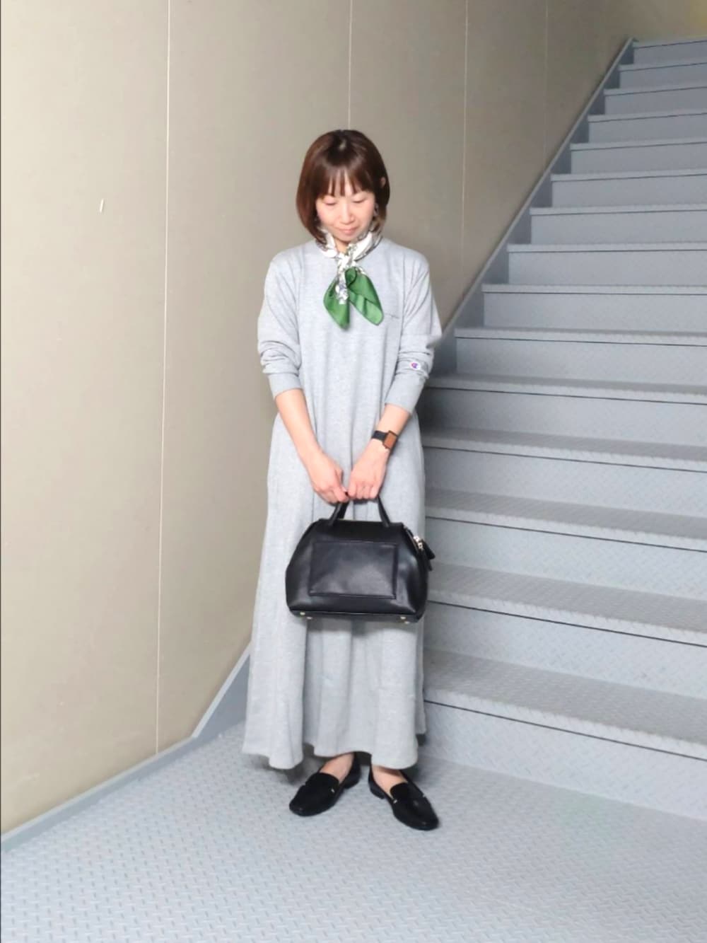 グレー系のワンピース、ブラック系のローファー、ブラック系のボストンバッグを着用したレディースの秋コーディネートの2枚目の写真