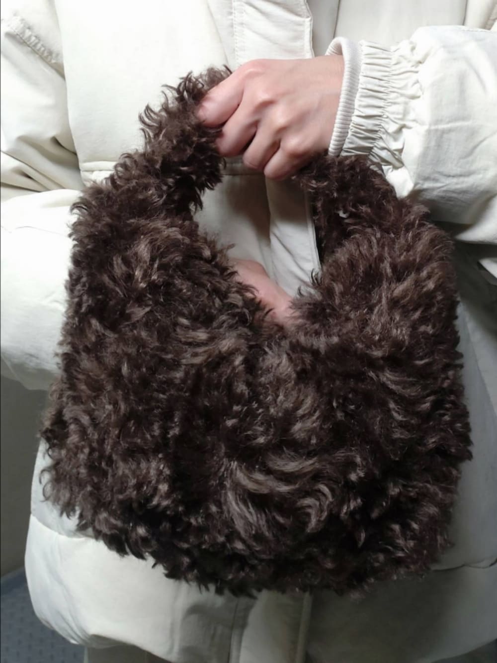 ホワイト系のダウンジャケット/コート、ホワイト系のその他パンツ、ブルー系のニット/セーターを着用したレディースの冬コーディネートの3枚目の写真