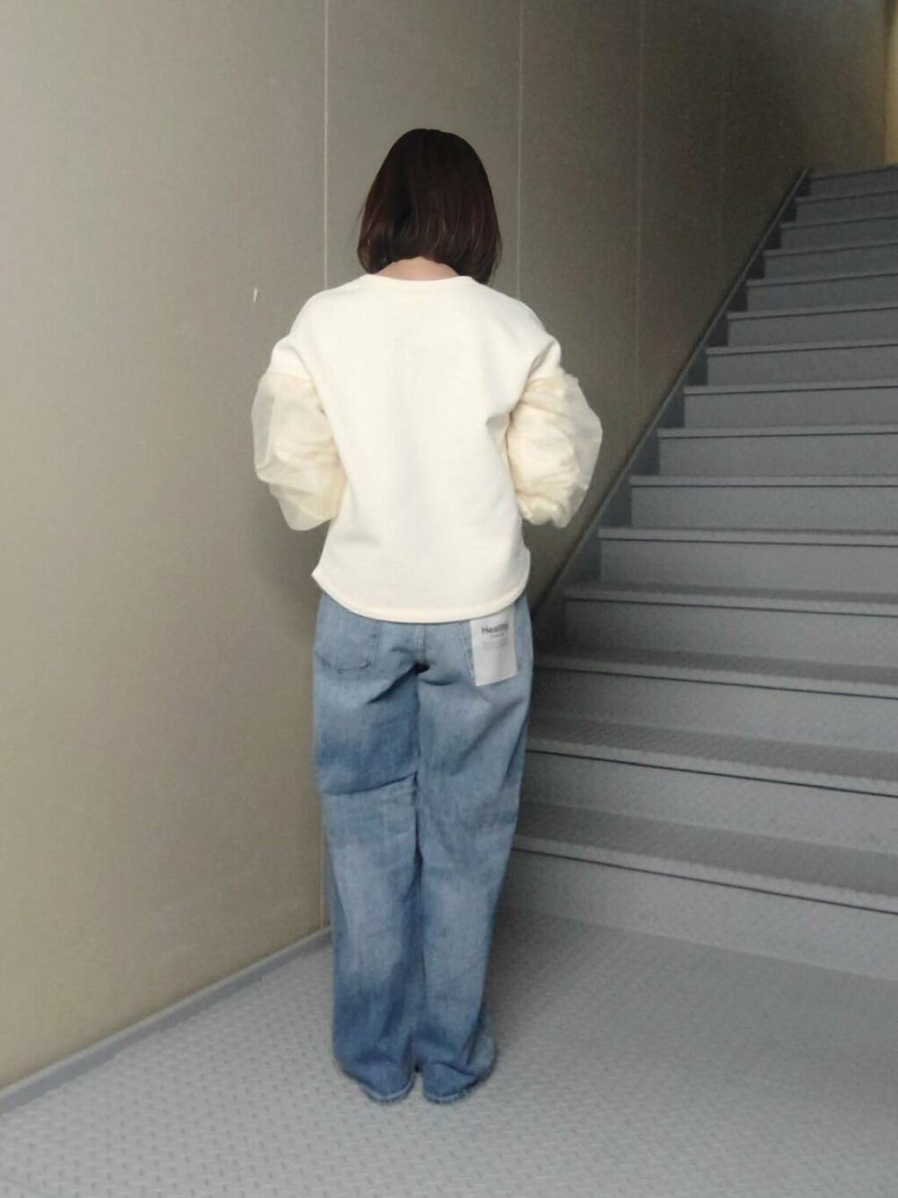 シルバー系のトートバッグ、ブラック系のローファー、ブルー系のデニムパンツを着用したレディースの冬コーディネートの2枚目の写真