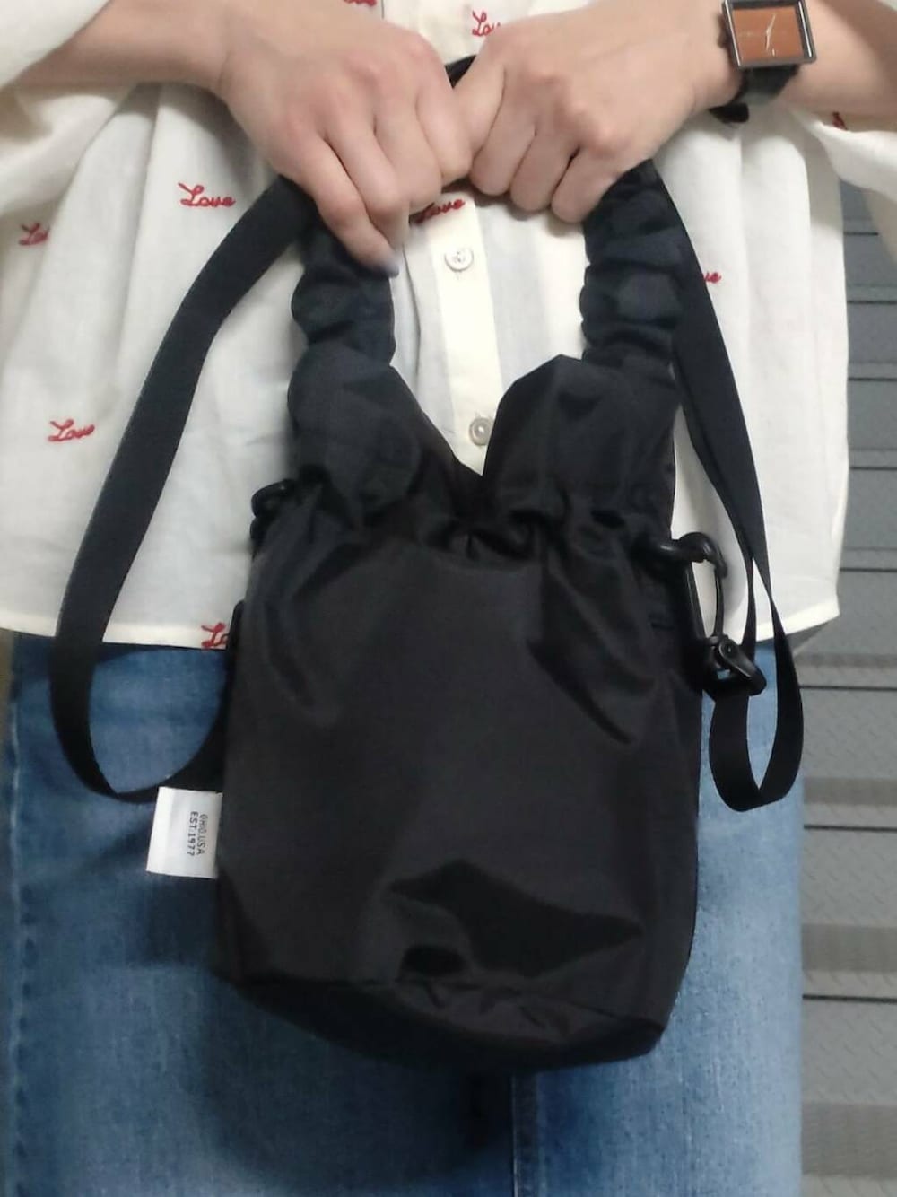 ブラック系のショルダーバッグ、ブラック系のサンダル、ブルー系のスカートを着用したレディースの春コーディネートの3枚目の写真