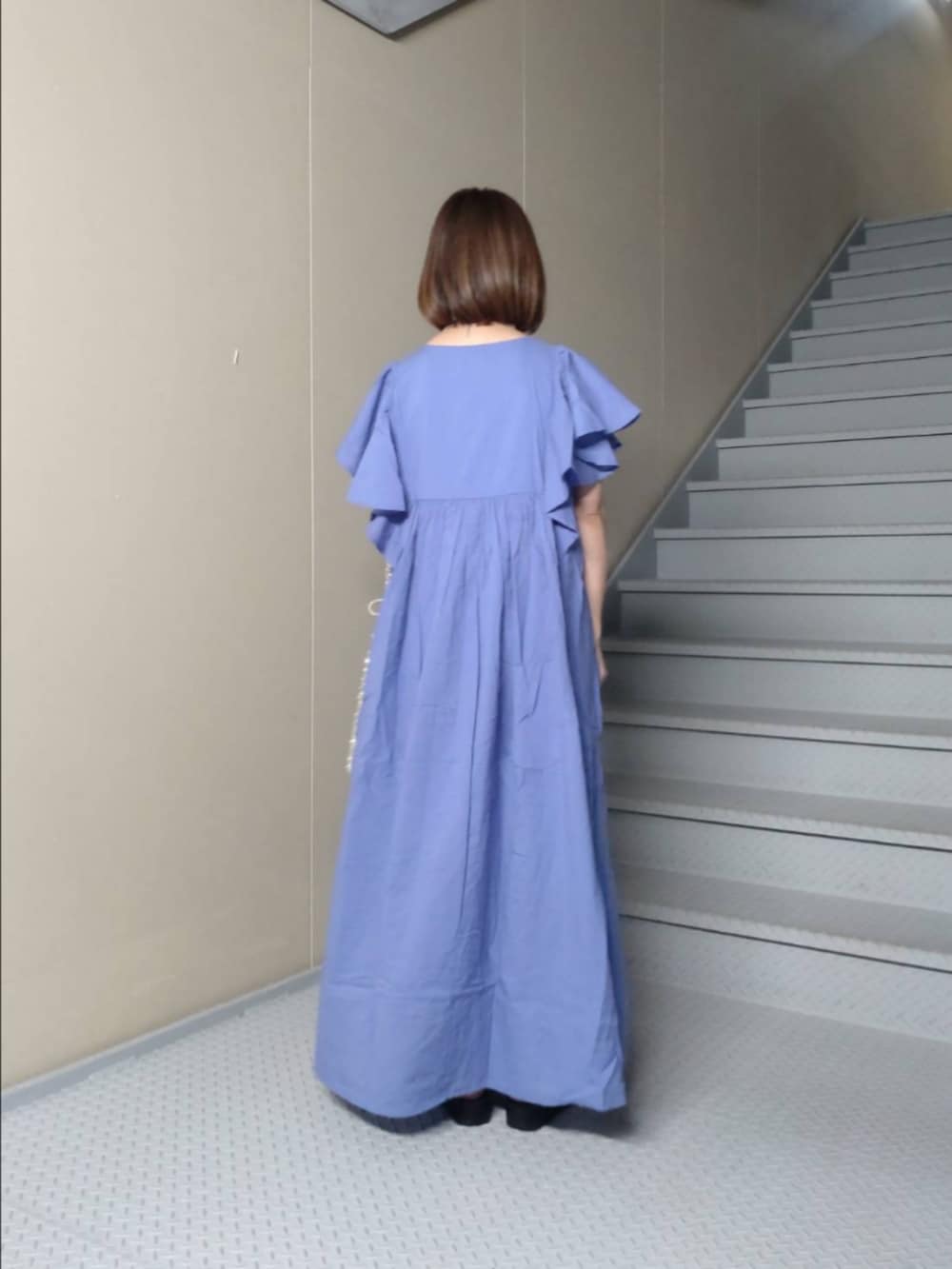 ブルー系のワンピース、ゴールド系のトートバッグ、ブラック系のサンダルを着用したレディースの春コーディネートの2枚目の写真