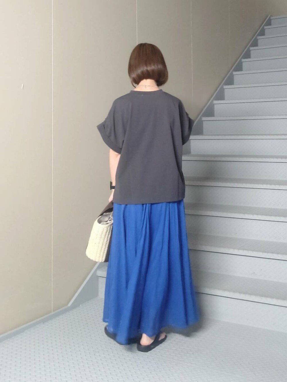 ホワイト系のハンドバッグ、ブルー系のスカート、グレー系のTシャツ/カットソーを着用したレディースの夏コーディネートの3枚目の写真