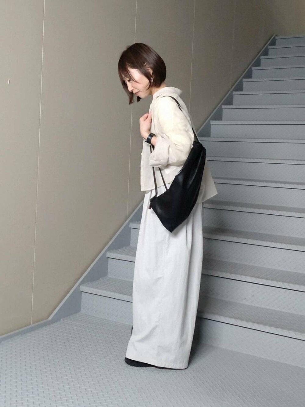 イエロー系のTシャツ/カットソー、ブラック系のバックパック/リュック、グレー系のその他パンツを着用したレディースの春コーディネートの2枚目の写真