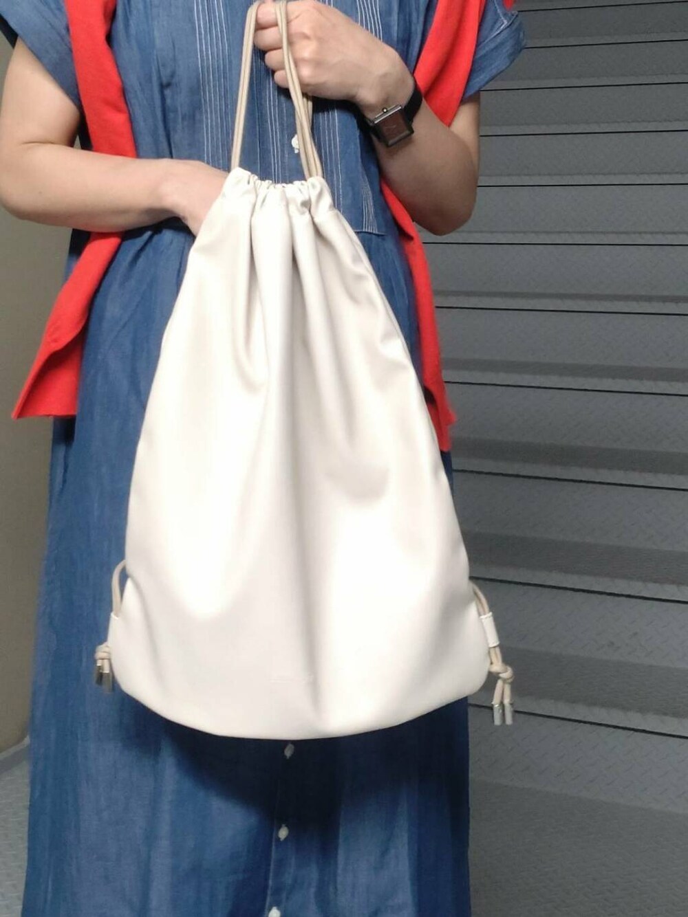 ホワイト系のバックパック/リュック、ブルー系のワンピース、レッド系のカーディガン/ボレロを着用したレディースの春コーディネートの4枚目の写真