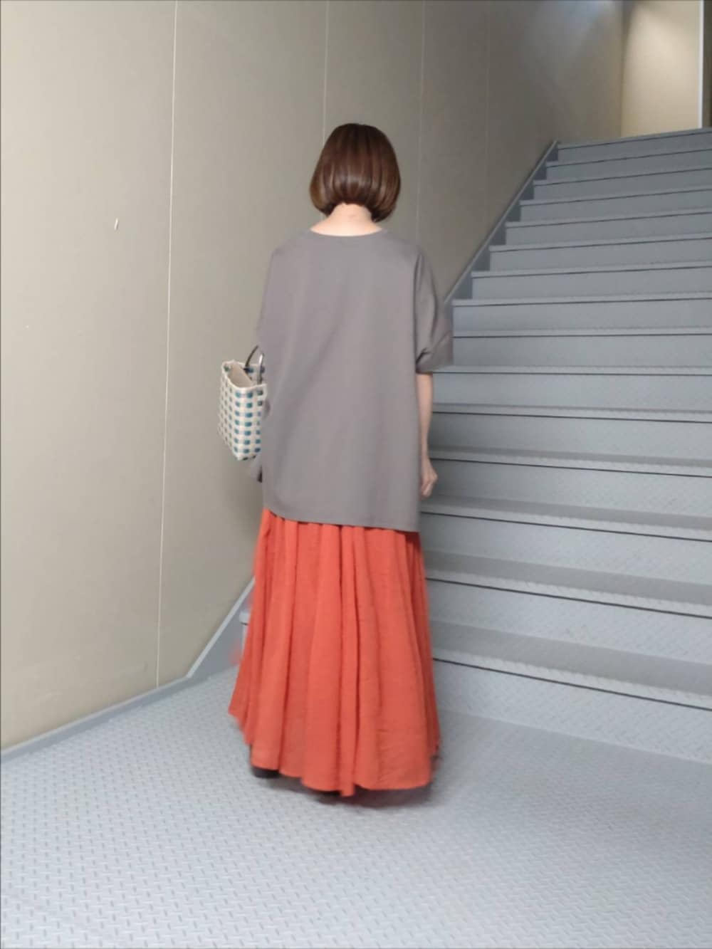 グレー系のTシャツ/カットソー、レッド系のスカート、ブラウン系のサンダルを着用したレディースの夏コーディネートの3枚目の写真