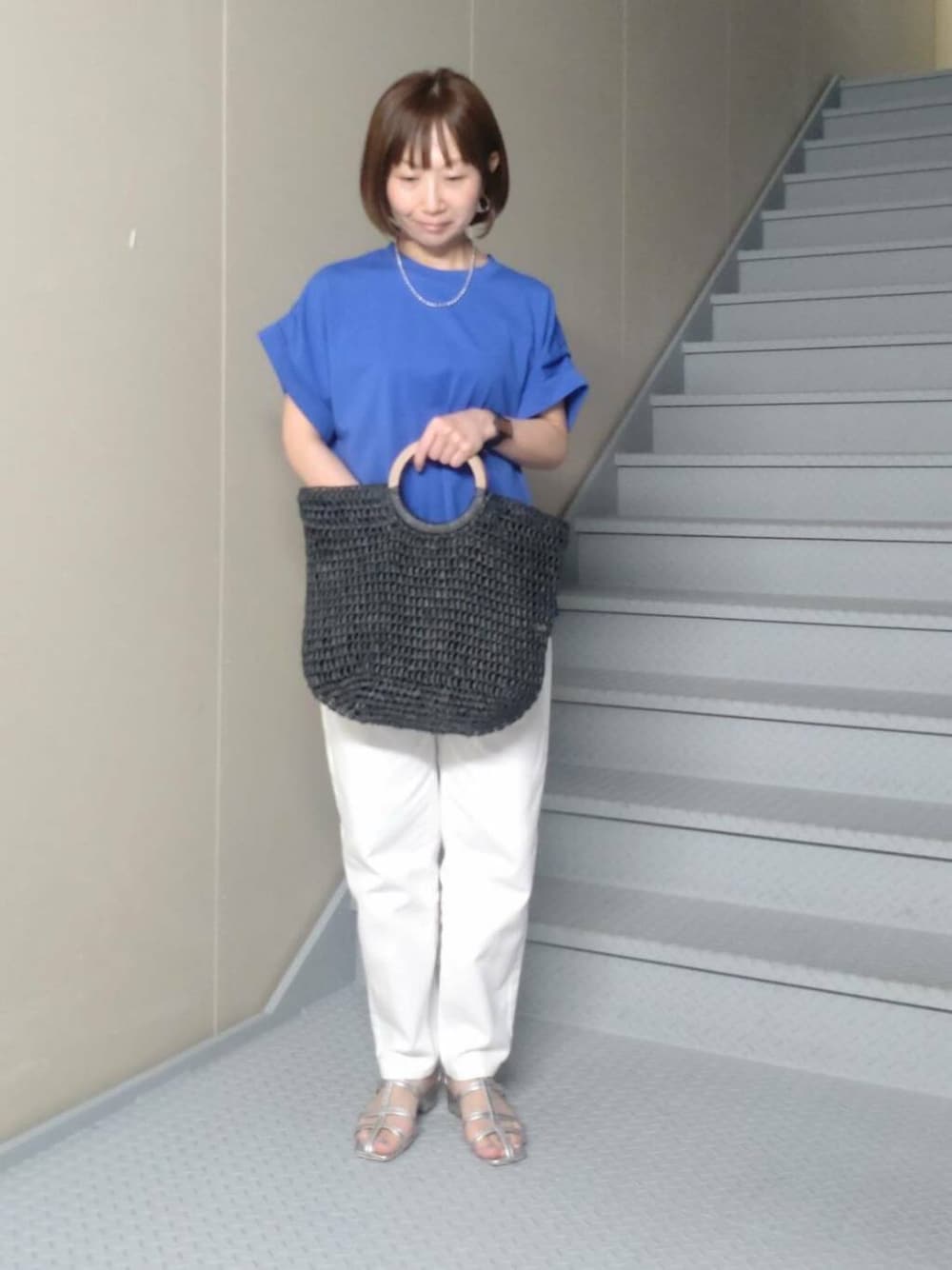 ブラック系のトートバッグ、シルバー系のサンダル、ホワイト系のデニムパンツを着用したレディースの夏コーディネートの2枚目の写真