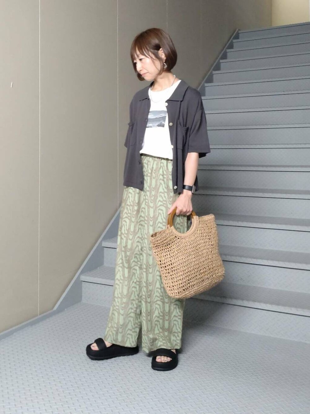 ベージュ系のトートバッグ、グレー系のニット/セーター、ホワイト系のTシャツ/カットソーを着用したレディースの春コーディネートの2枚目の写真