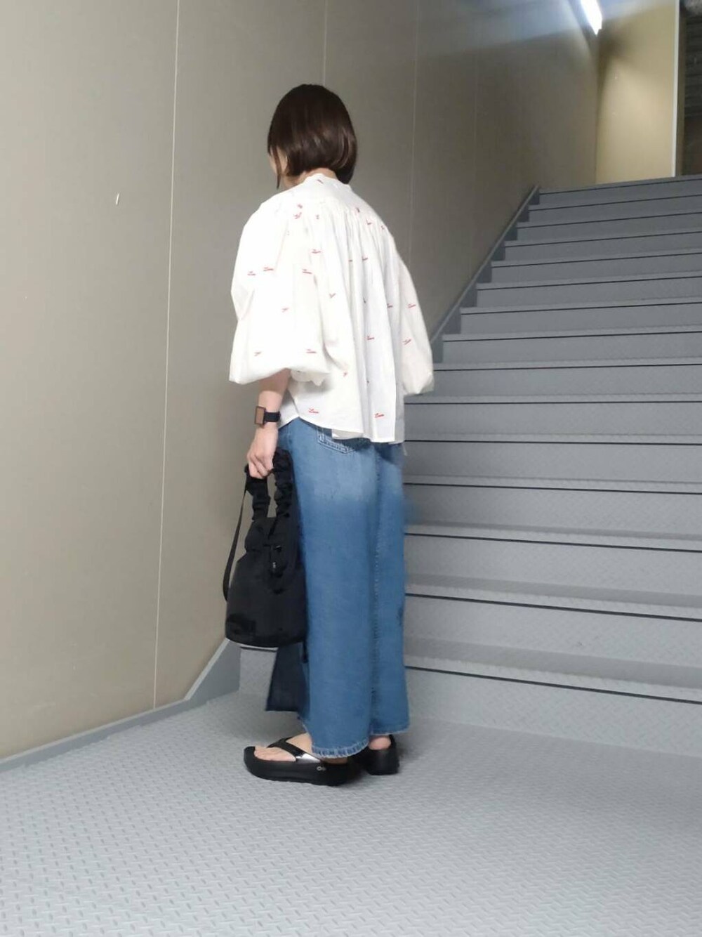 ブラック系のショルダーバッグ、ブラック系のサンダル、ブルー系のスカートを着用したレディースの春コーディネートの2枚目の写真