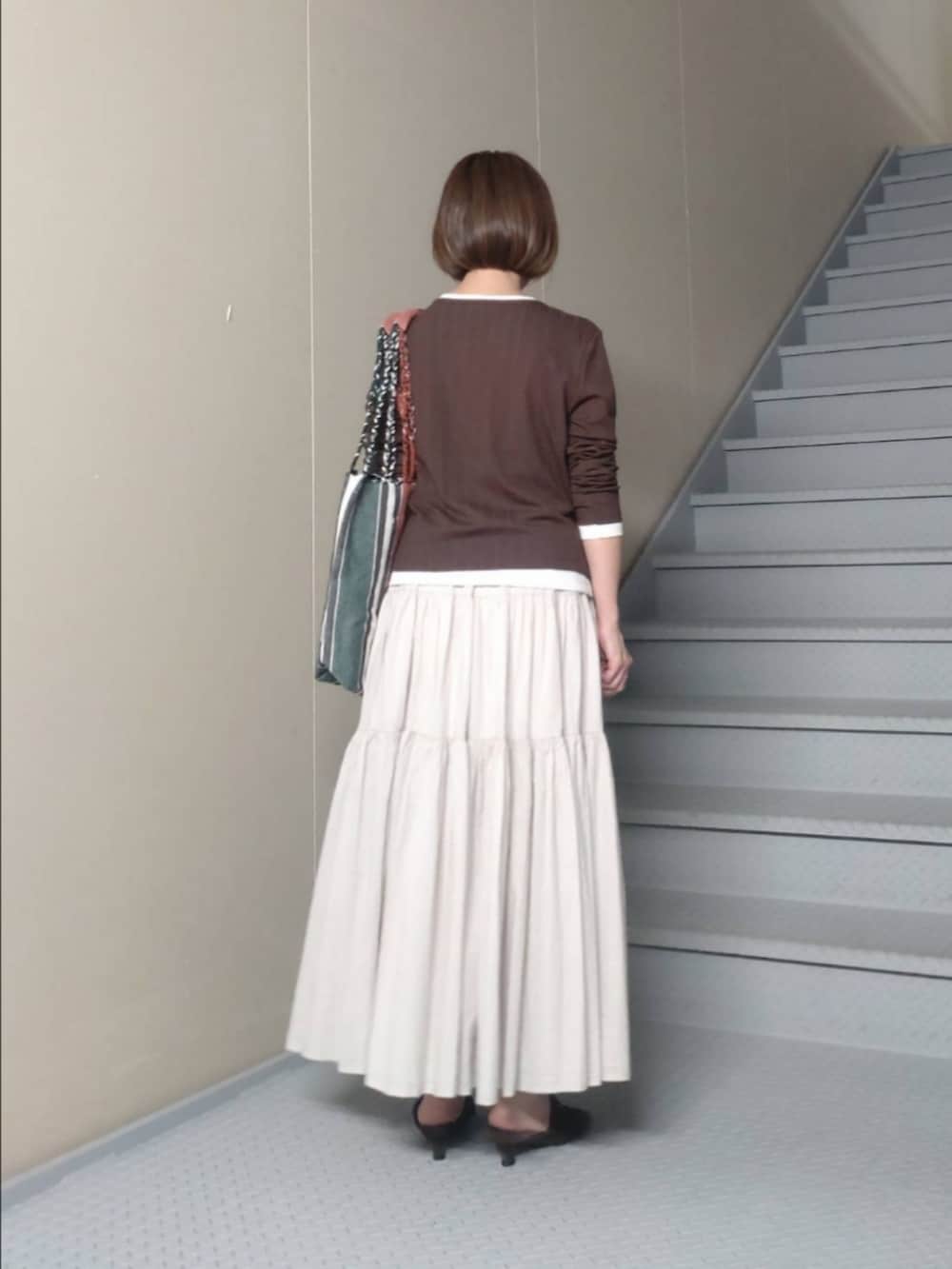 ブラウン系のTシャツ/カットソー、グレー系のスカート、グリーン系のトートバッグを着用したレディースの夏コーディネートの2枚目の写真