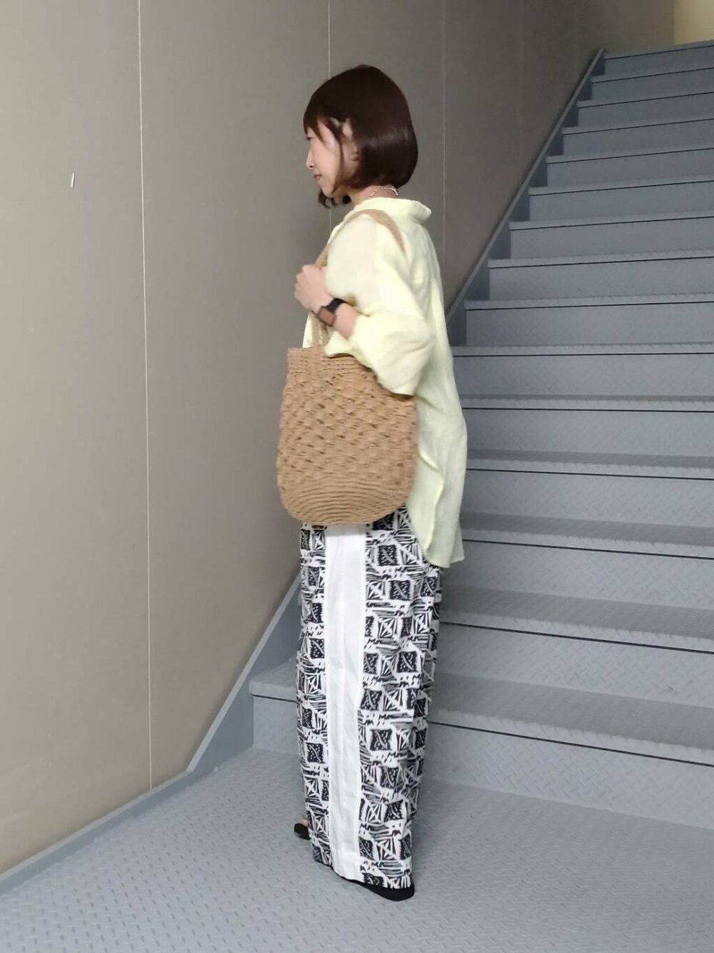 ホワイト系のタンクトップ、ブラック系のサンダル、ベージュ系のトートバッグを着用したレディースの春コーディネートの3枚目の写真