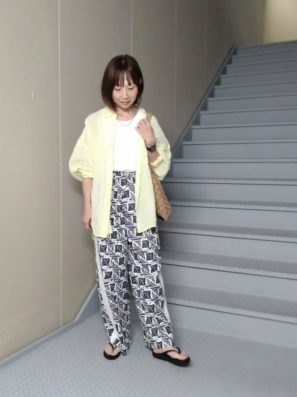 ホワイト系のタンクトップ、ブラック系のサンダル、ベージュ系のトートバッグを着用したレディースの春コーディネートの2枚目の写真