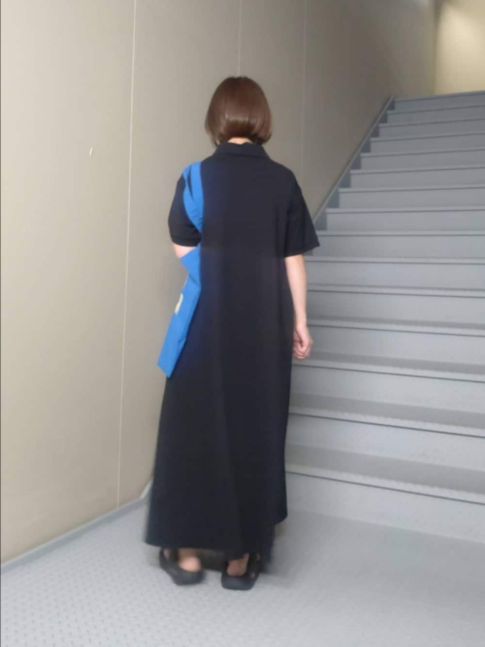 ブラック系のワンピース、ブルー系のトートバッグ、ホワイト系のネックレスを着用したレディースの夏コーディネートの2枚目の写真