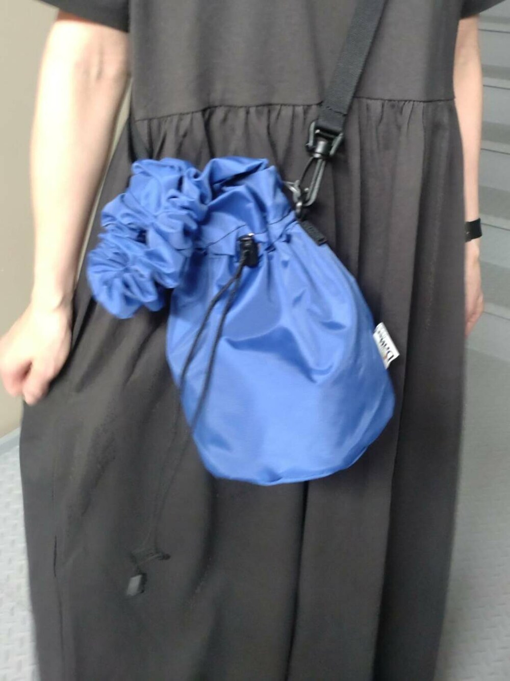 ブルー系のショルダーバッグ、ブラック系のワンピースを着用したレディースの春コーディネートの3枚目の写真