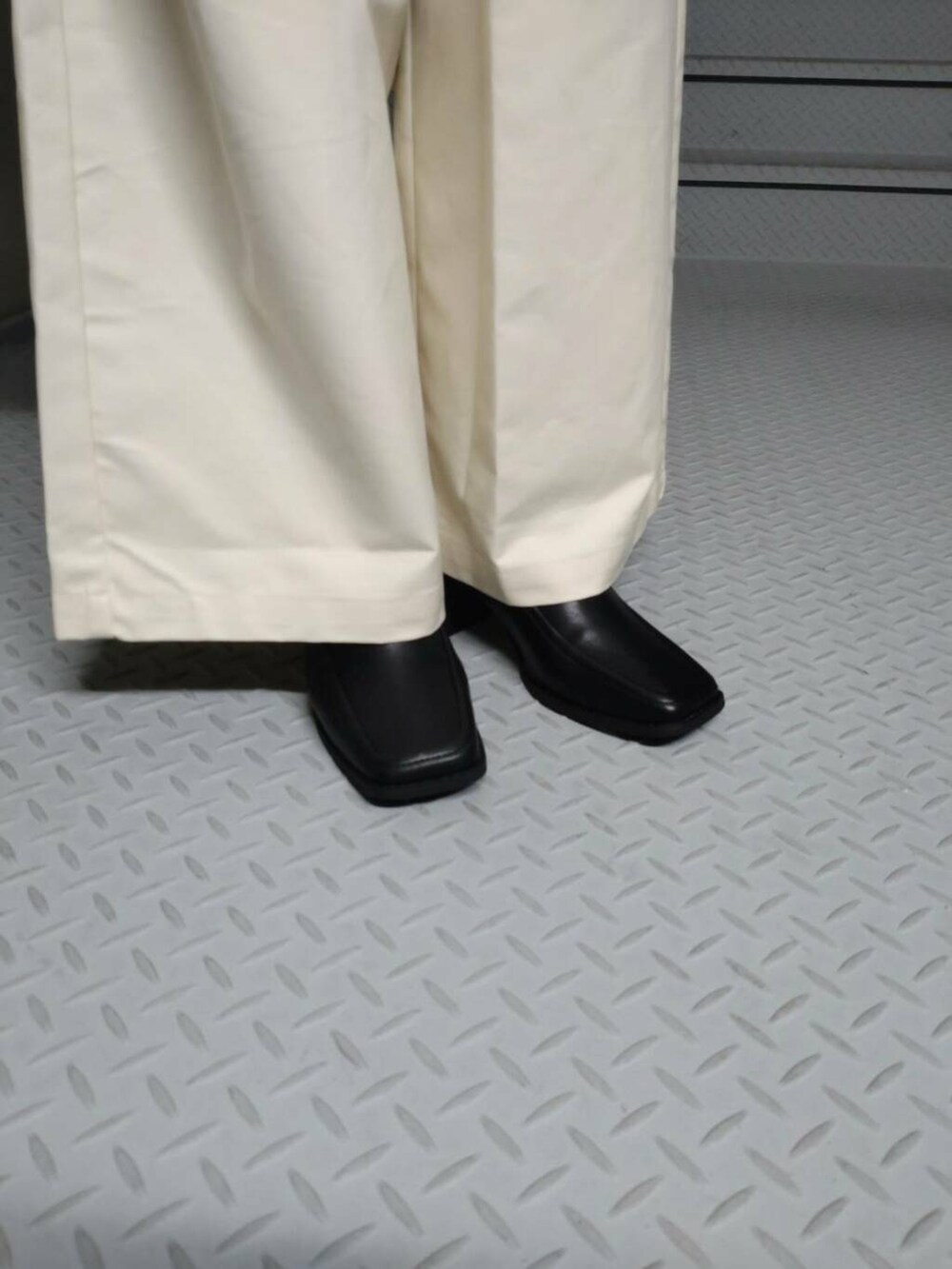 ホワイト系のタンクトップ、グリーン系のカーディガン/ボレロ、ブラック系のブーツを着用したレディースの秋コーディネートの3枚目の写真