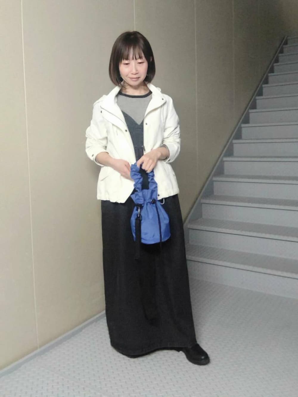 ブルー系のショルダーバッグ、ホワイト系のマウンテンパーカー、ブラック系のTシャツ/カットソーを着用したレディースの春コーディネートの2枚目の写真