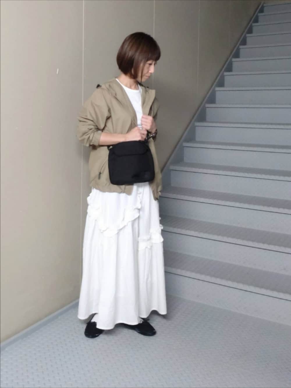 ホワイト系のスカート、グリーン系のナイロンジャケット、ホワイト系のTシャツ/カットソーを着用したレディースの秋コーディネートの2枚目の写真