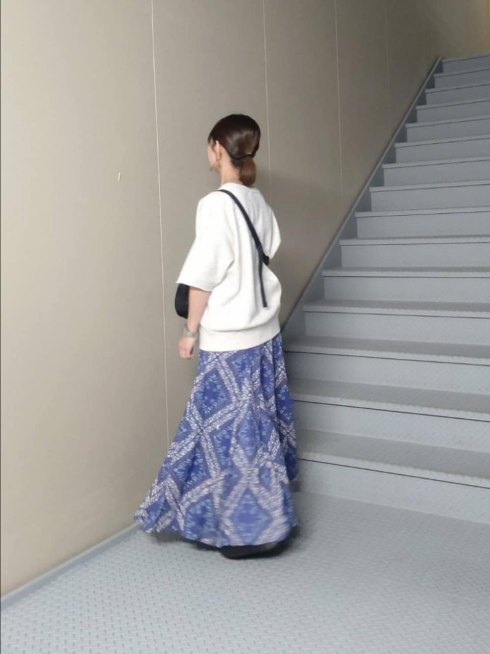 ブルー系のスカート、ホワイト系のスウェット、ブラック系のショルダーバッグを着用したレディースの春コーディネートの2枚目の写真