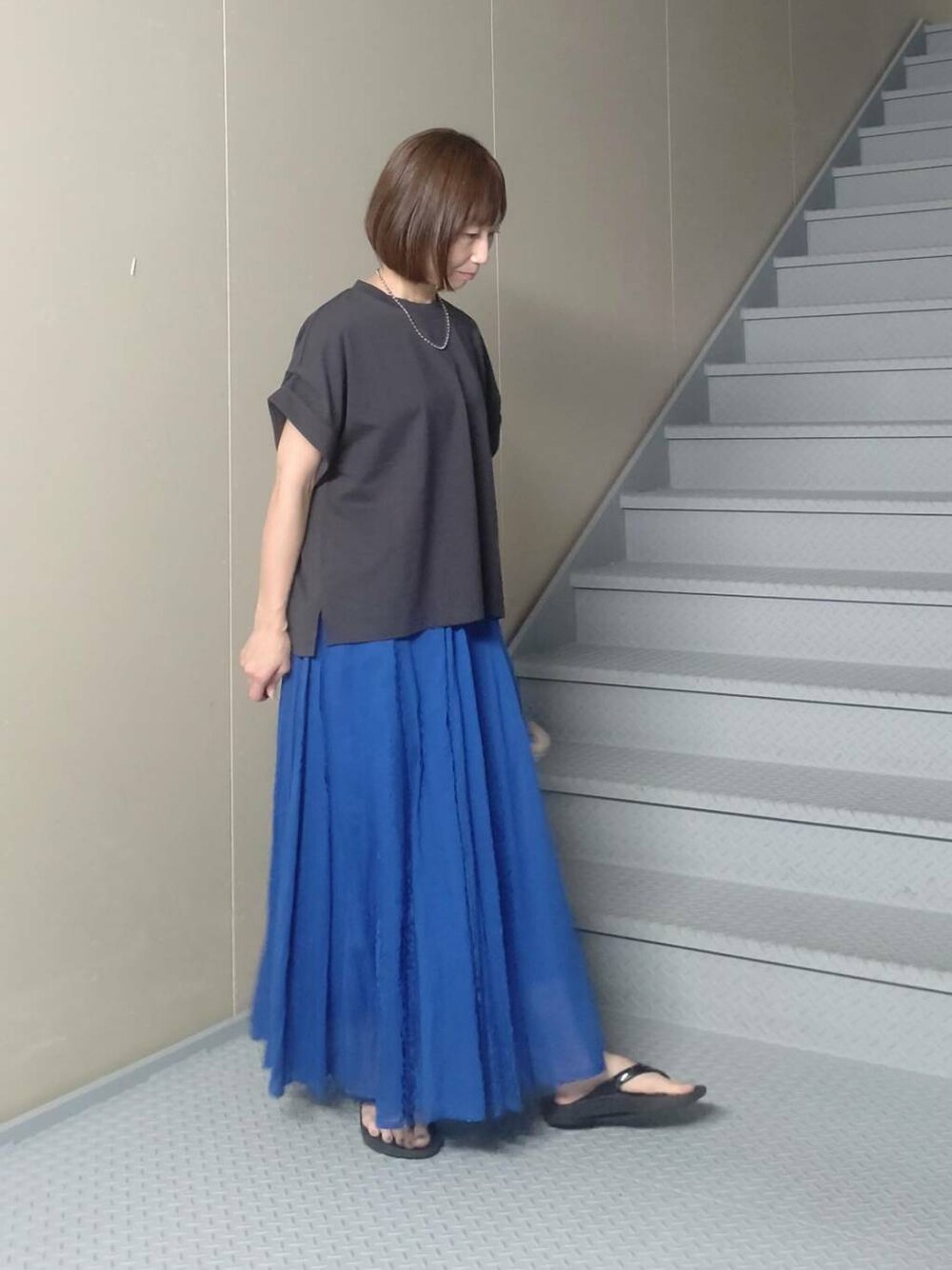 ホワイト系のハンドバッグ、ブルー系のスカート、グレー系のTシャツ/カットソーを着用したレディースの夏コーディネートの2枚目の写真