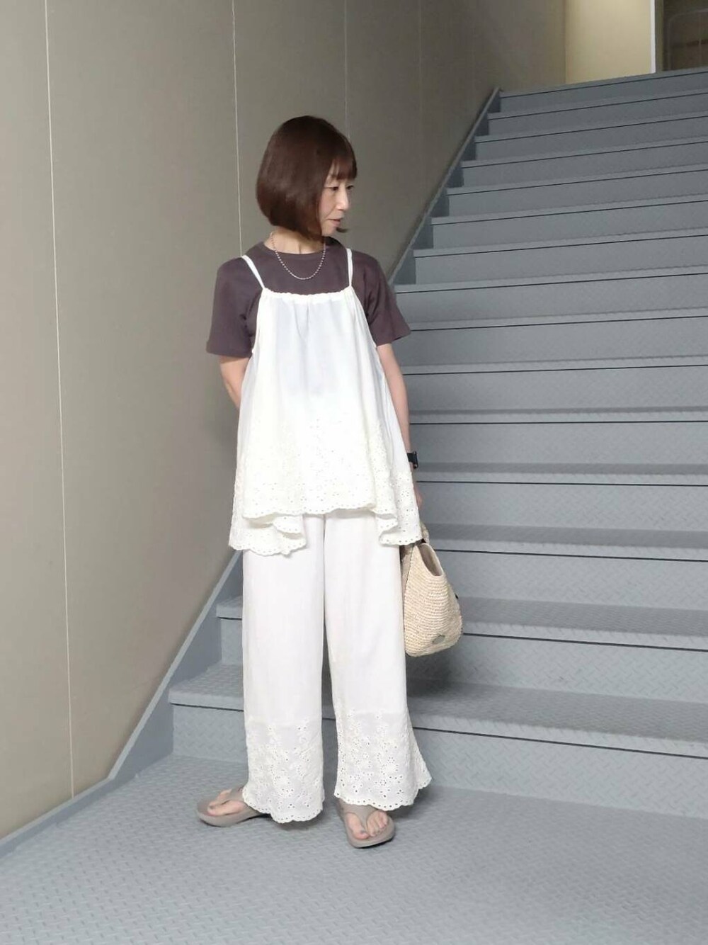 ゴールド系のかごバッグ、ベージュ系のサンダル、ブラウン系のTシャツ/カットソーを着用したレディースの春コーディネートの2枚目の写真