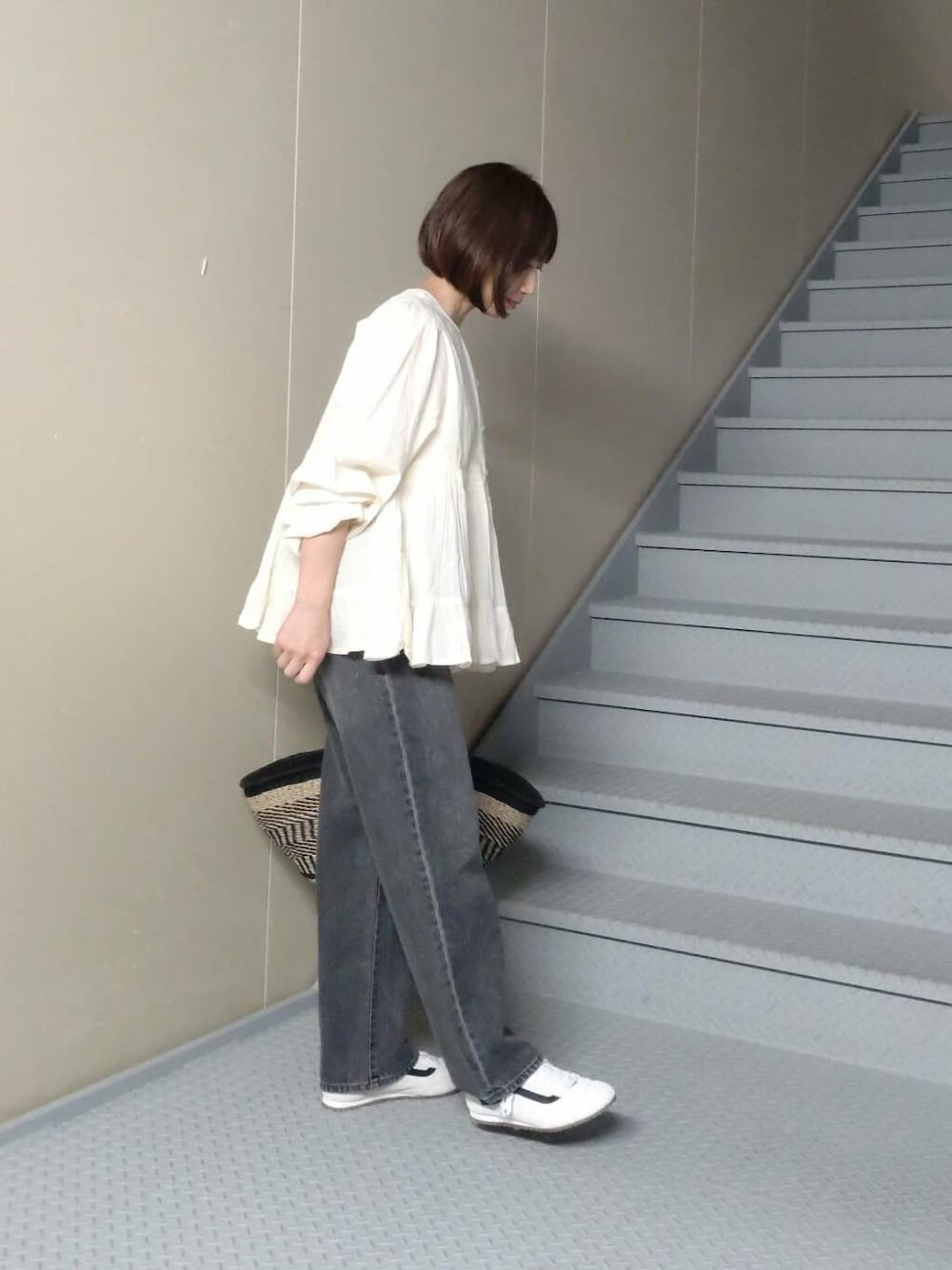 ブラック系のデニムパンツ、ベージュ系のかごバッグ、ホワイト系のシャツ/ブラウスを着用したレディースの春コーディネートの2枚目の写真