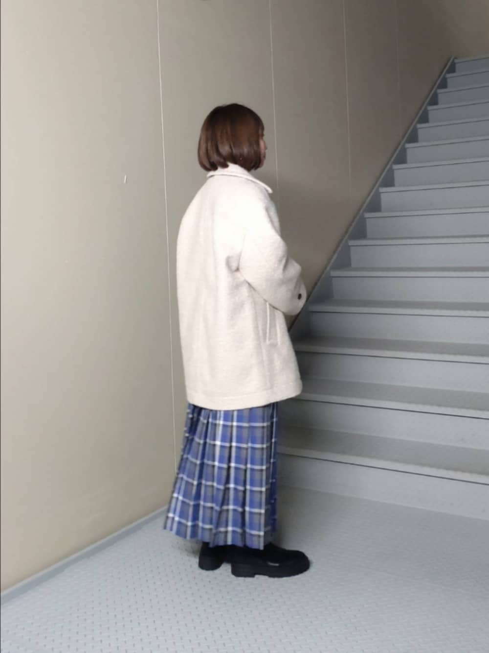 ホワイト系のその他アウター、ブルー系のスカート、ブラック系のハンドバッグを着用したレディースの秋コーディネートの2枚目の写真