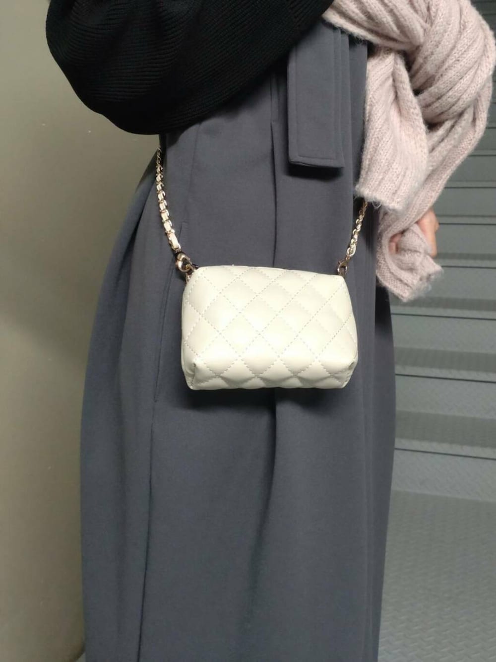 ホワイト系のショルダーバッグ、グレー系のジャンパースカート、ブラック系のニット/セーターを着用したレディースの冬コーディネートの3枚目の写真