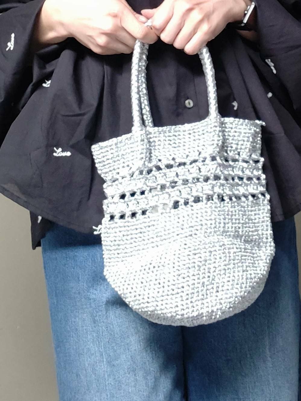 シルバー系のショルダーバッグ、ブルー系のデニムパンツ、ブラック系のシャツ/ブラウスを着用したレディースの春コーディネートの3枚目の写真