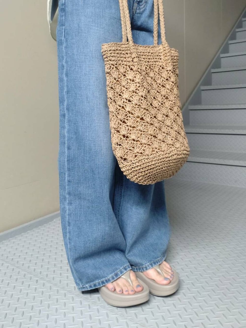 ブルー系のデニムパンツ、ベージュ系のサンダル、ベージュ系のトートバッグを着用したレディースの夏コーディネートの4枚目の写真