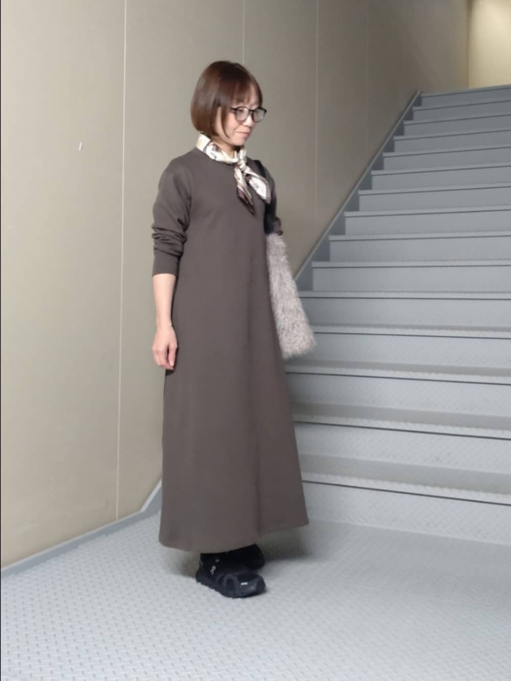 グレー系のワンピース、グレー系のトートバッグ、ブラウン系のバンダナ/スカーフを着用したレディースの秋コーディネートの2枚目の写真