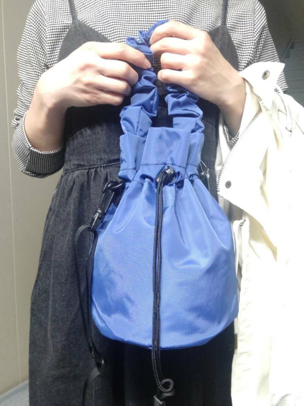 ブルー系のショルダーバッグ、ホワイト系のマウンテンパーカー、ブラック系のTシャツ/カットソーを着用したレディースの春コーディネートの3枚目の写真