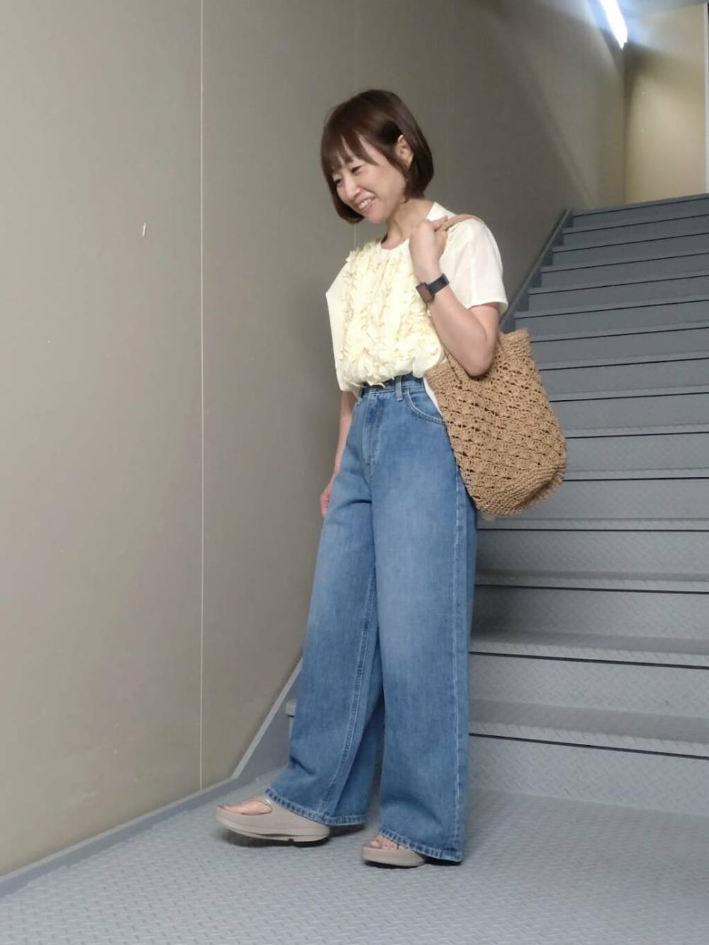 ブルー系のデニムパンツ、ベージュ系のサンダル、ベージュ系のトートバッグを着用したレディースの夏コーディネートの2枚目の写真