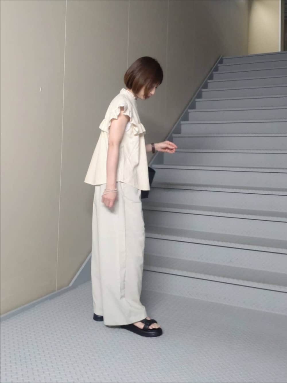ベージュ系のシャツ/ブラウス、ホワイト系のその他パンツ、ブラック系のハンドバッグを着用したレディースの夏コーディネートの2枚目の写真