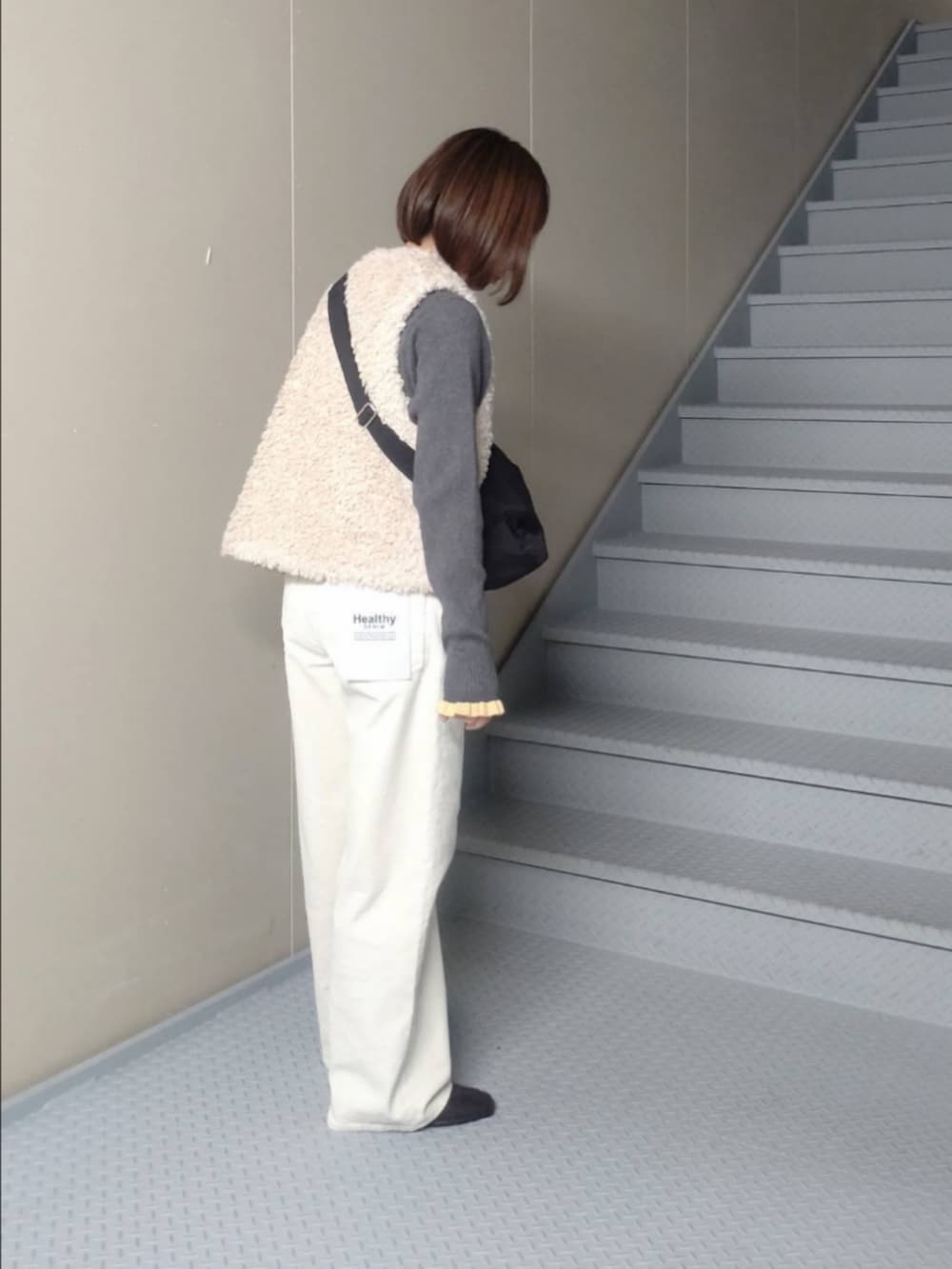 グレー系のニット/セーター、ホワイト系のその他パンツ、ブラック系のショルダーバッグを着用したレディースの秋コーディネートの2枚目の写真