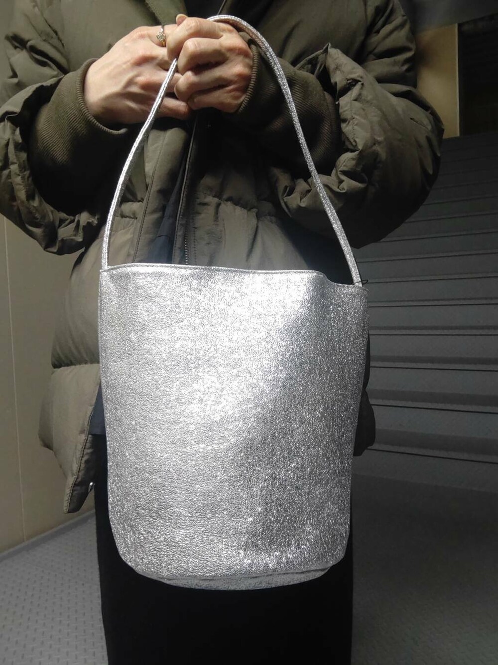 グリーン系のダウンジャケット/コート、ブラック系のローファー、シルバー系のハンドバッグを着用したレディースの冬コーディネートの3枚目の写真