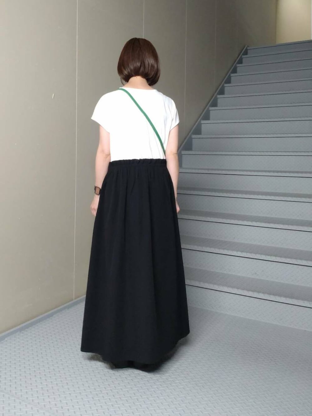 グリーン系のショルダーバッグ、ブラック系のサンダル、ブラック系のワンピースを着用したレディースの夏コーディネートの2枚目の写真