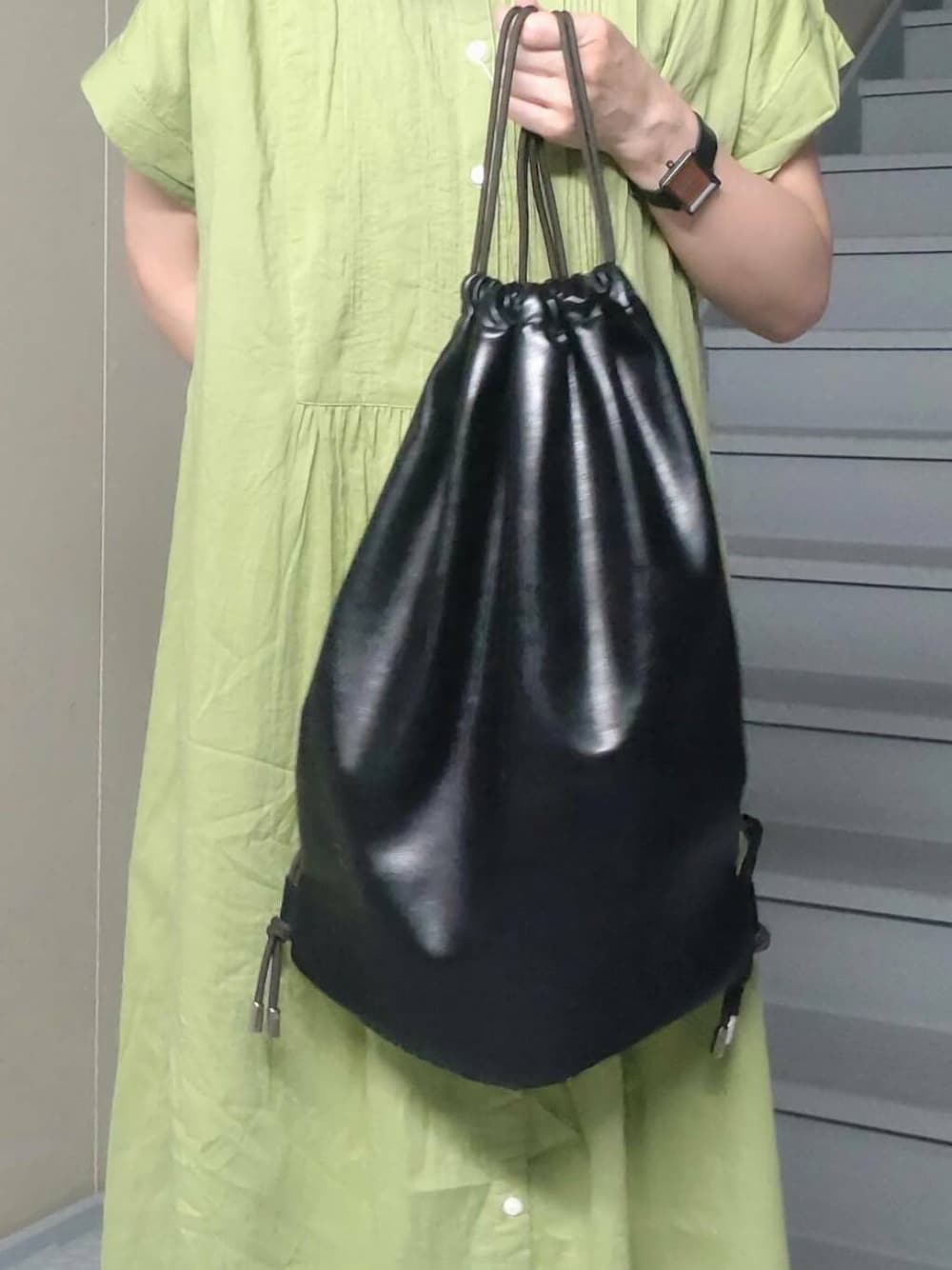 ブラック系のバックパック/リュック、グリーン系のワンピース、ブラック系のサンダルを着用したレディースの夏コーディネートの3枚目の写真