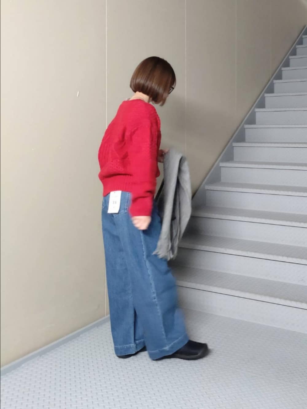 レッド系のニット/セーター、ブルー系のデニムパンツ、ブラック系のハンドバッグを着用したレディースの冬コーディネートの2枚目の写真