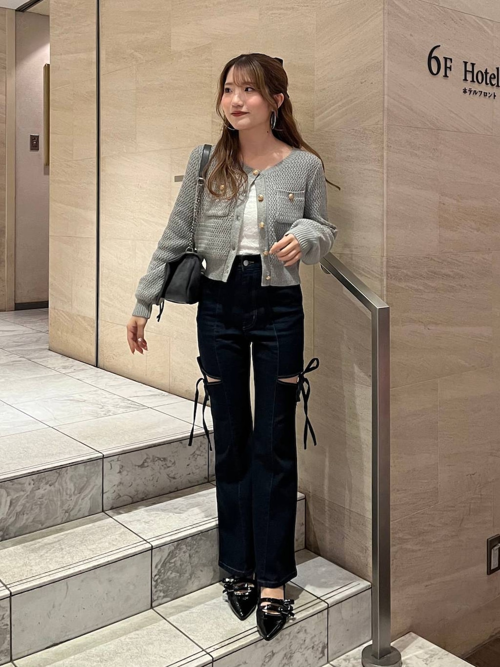 グレー系のショルダーバッグ、ブラック系のパンプス、ブルー系のデニムパンツを着用したレディースの春コーディネートの2枚目の写真