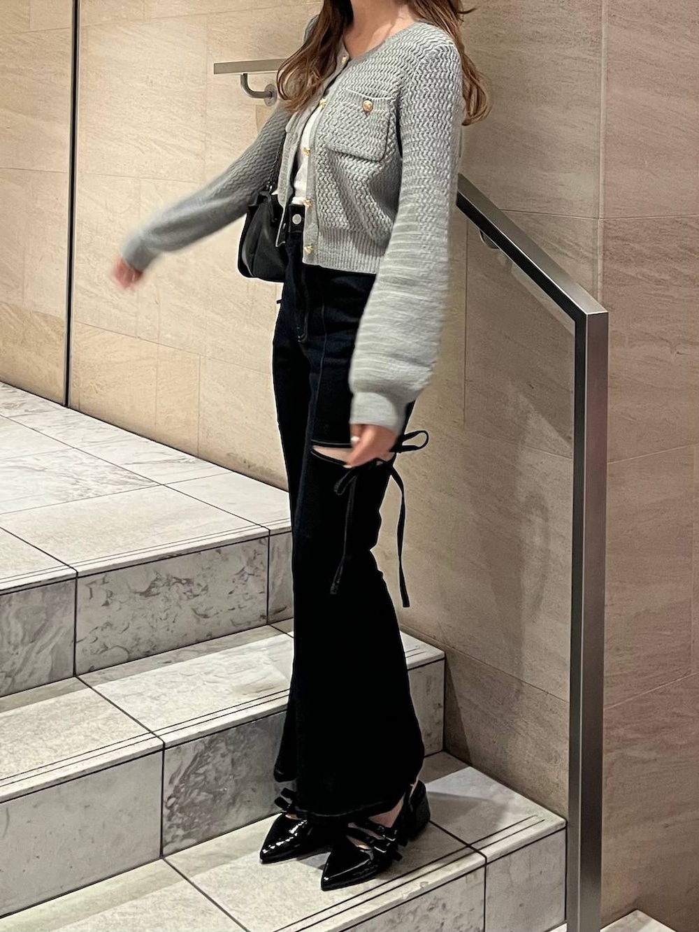 グレー系のショルダーバッグ、ブラック系のパンプス、ブルー系のデニムパンツを着用したレディースの春コーディネートの3枚目の写真