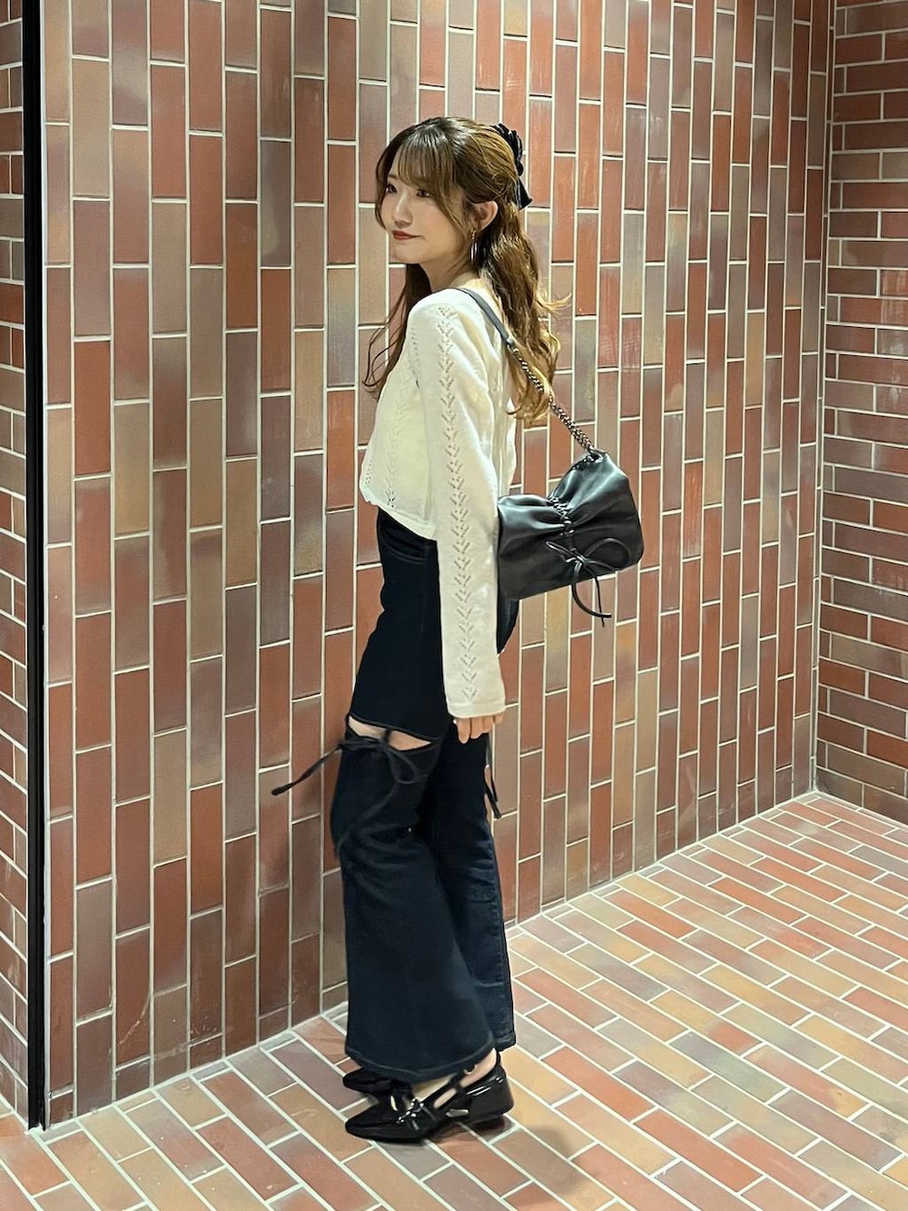 グレー系のショルダーバッグ、ブラック系のパンプス、ブルー系のデニムパンツを着用したレディースの春コーディネートの2枚目の写真