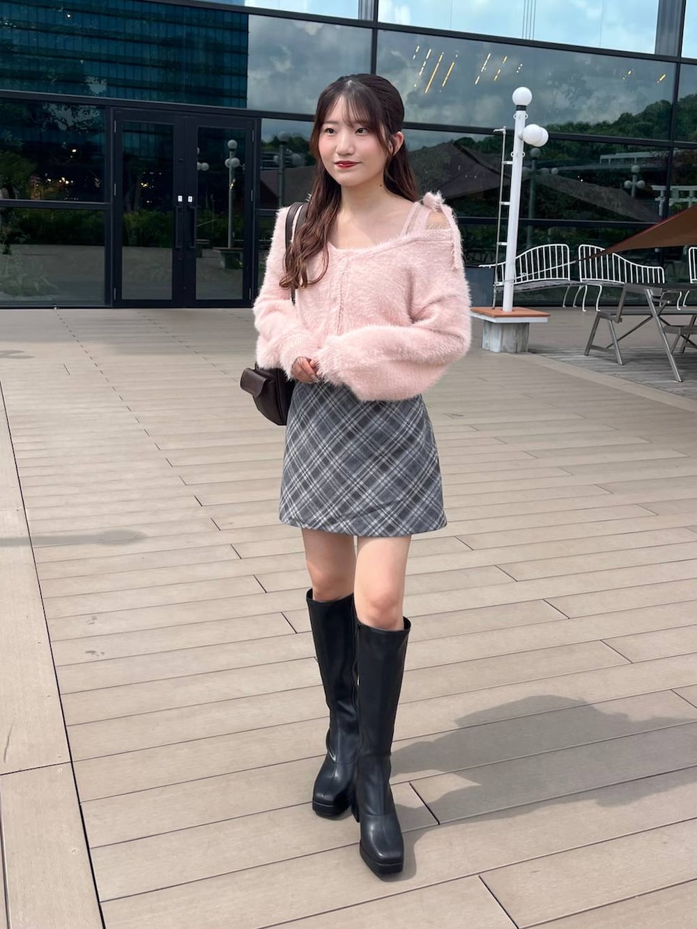 ブラック系のブーツ、グレー系のスカート、ブラウン系のボストンバッグを着用したレディースの秋コーディネートの2枚目の写真