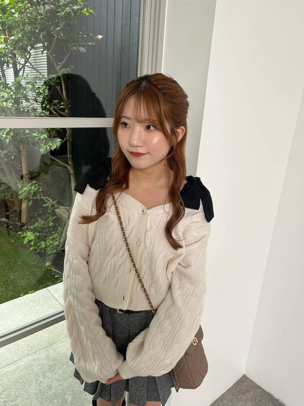 ブラック系のブーツ、グレー系のスカート、ベージュ系のショルダーバッグを着用したレディースの秋コーディネートの4枚目の写真
